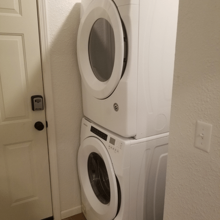 A washer and dryer are stacked on top of each other in a laundry room.