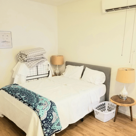 A bedroom with a bed a lamp and a basket
