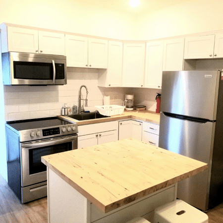 A kitchen with a stove , refrigerator , microwave and sink.