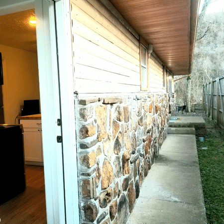 A stone wall along the side of a house
