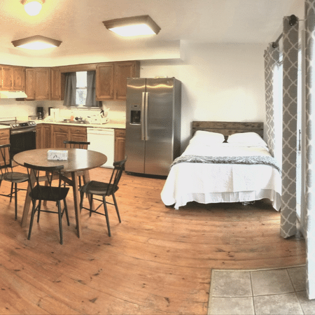 A bedroom with a table and chairs and a refrigerator