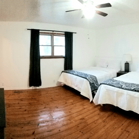 A bedroom with two beds and a ceiling fan