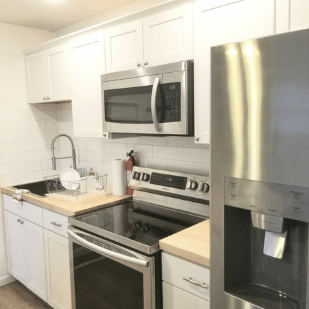 A kitchen with a stove , microwave , refrigerator and sink
