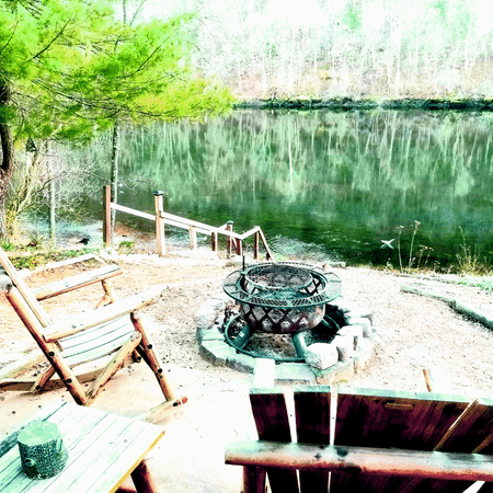 A fire pit is in the middle of a patio next to a lake.