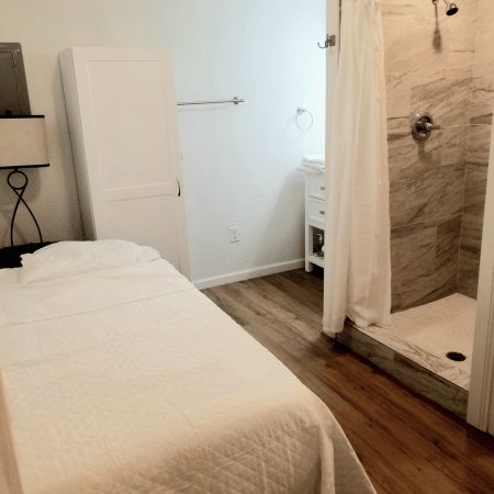 A bedroom with a single bed and a walk in shower