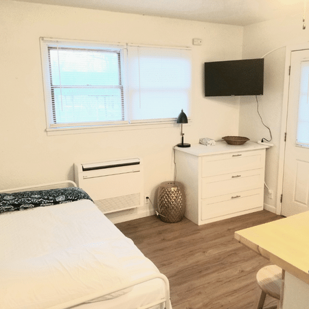A bedroom with a bed , dresser , television and window.