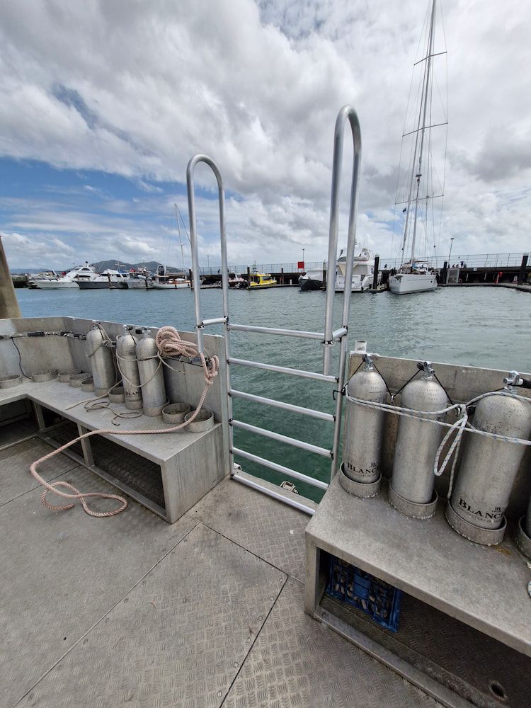 a Boat Deck With Diving Tanks, Ladder, and Harbor View on a Cloudy Day — Cairns Metal Works in Portsmith, QLD