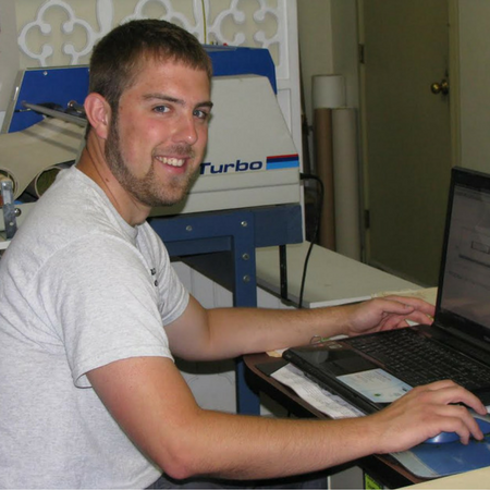 Man sitting at a desk using a laptop, smiling in a home office