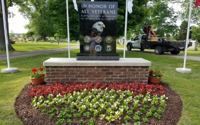 Memorial monument honoring all veterans with flowers and flags in a park setting