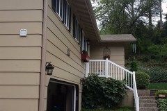 A house with a white railing and stairs leading up to it.