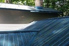 A close up of a metal roof with a chimney on top of it.