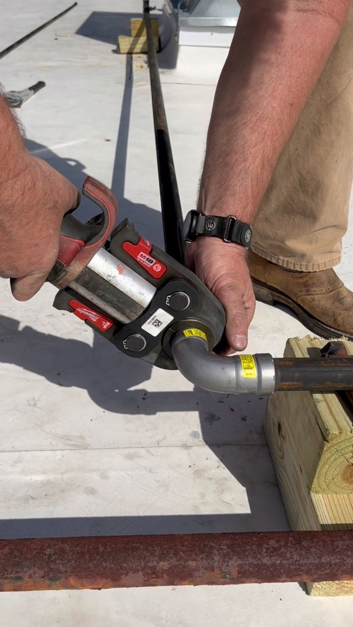 A man is using a pipe cutter to cut a pipe.