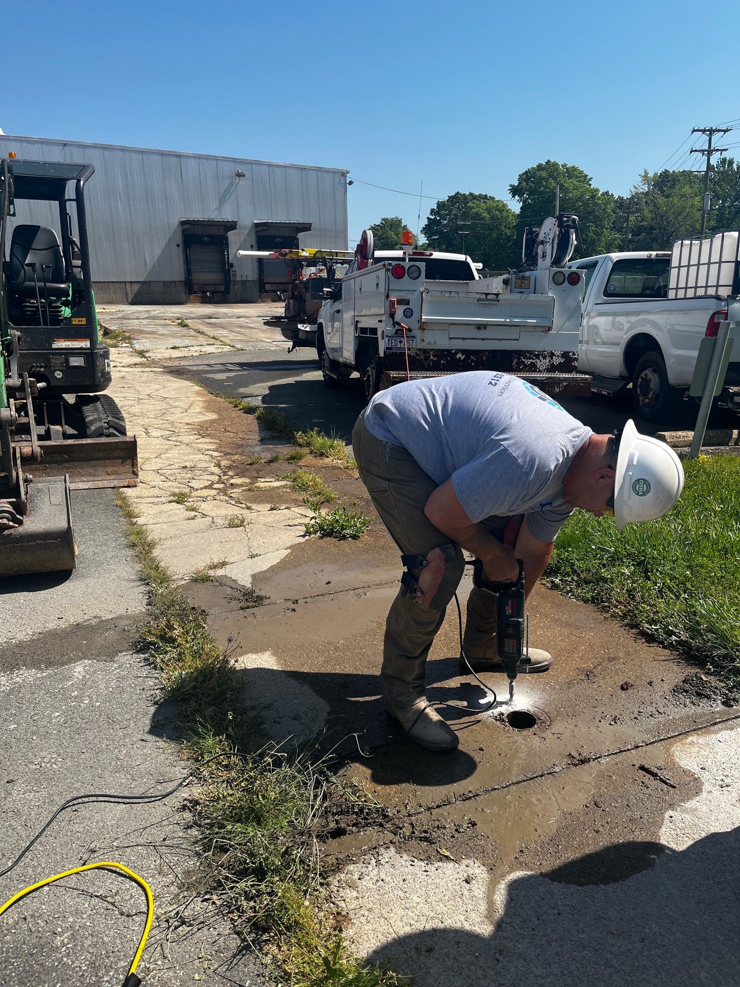 A man is using a drill to drill a hole in the ground.