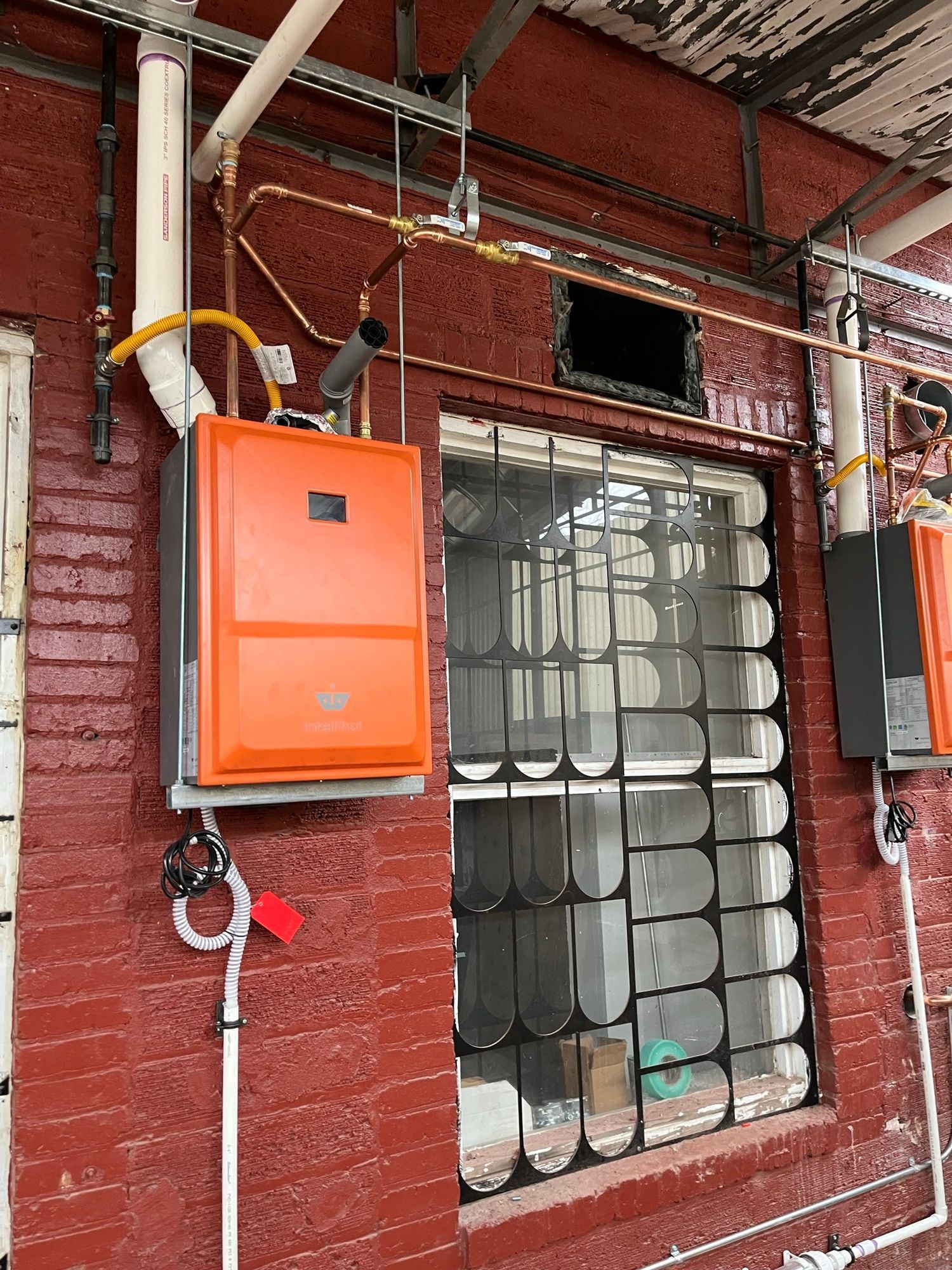 A brick building with a window and a box on the side of it.