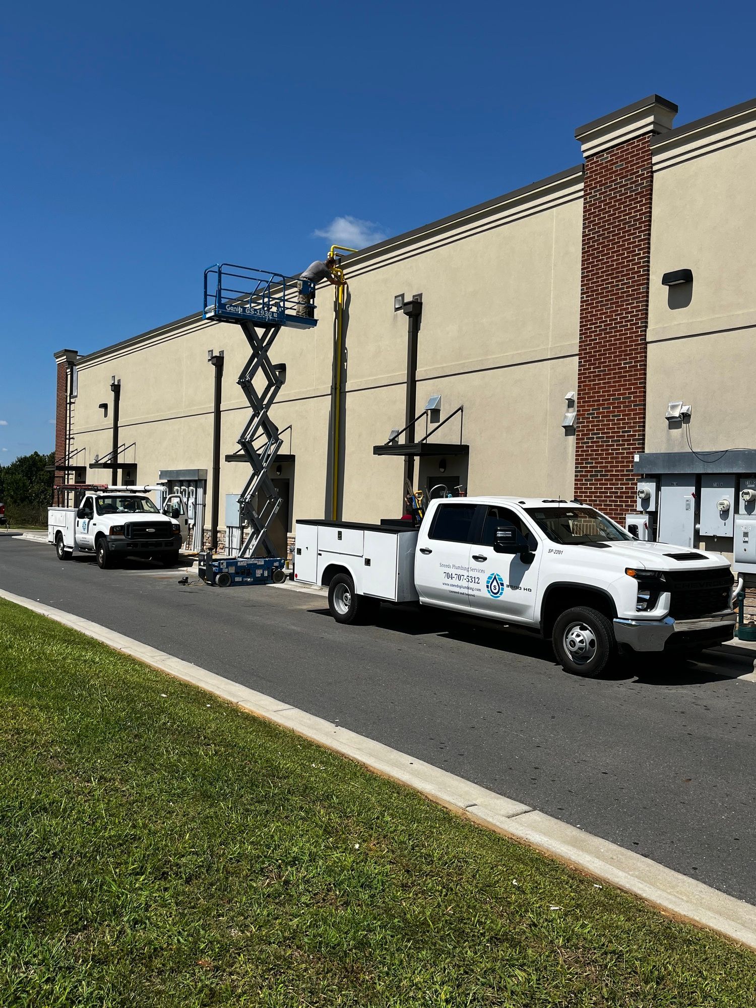 Two white trucks are parked in front of a large building.