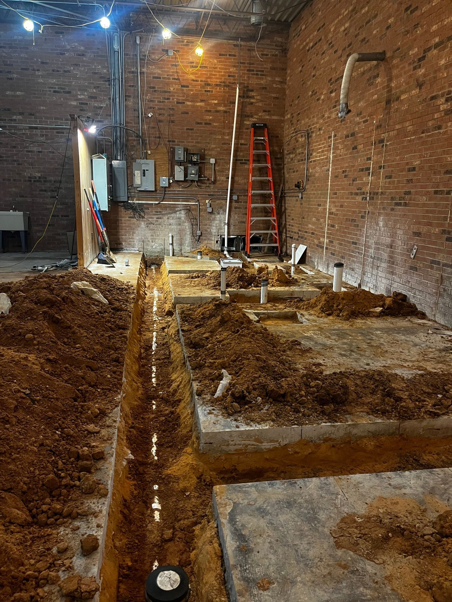 A room with a lot of dirt and a ladder in it.