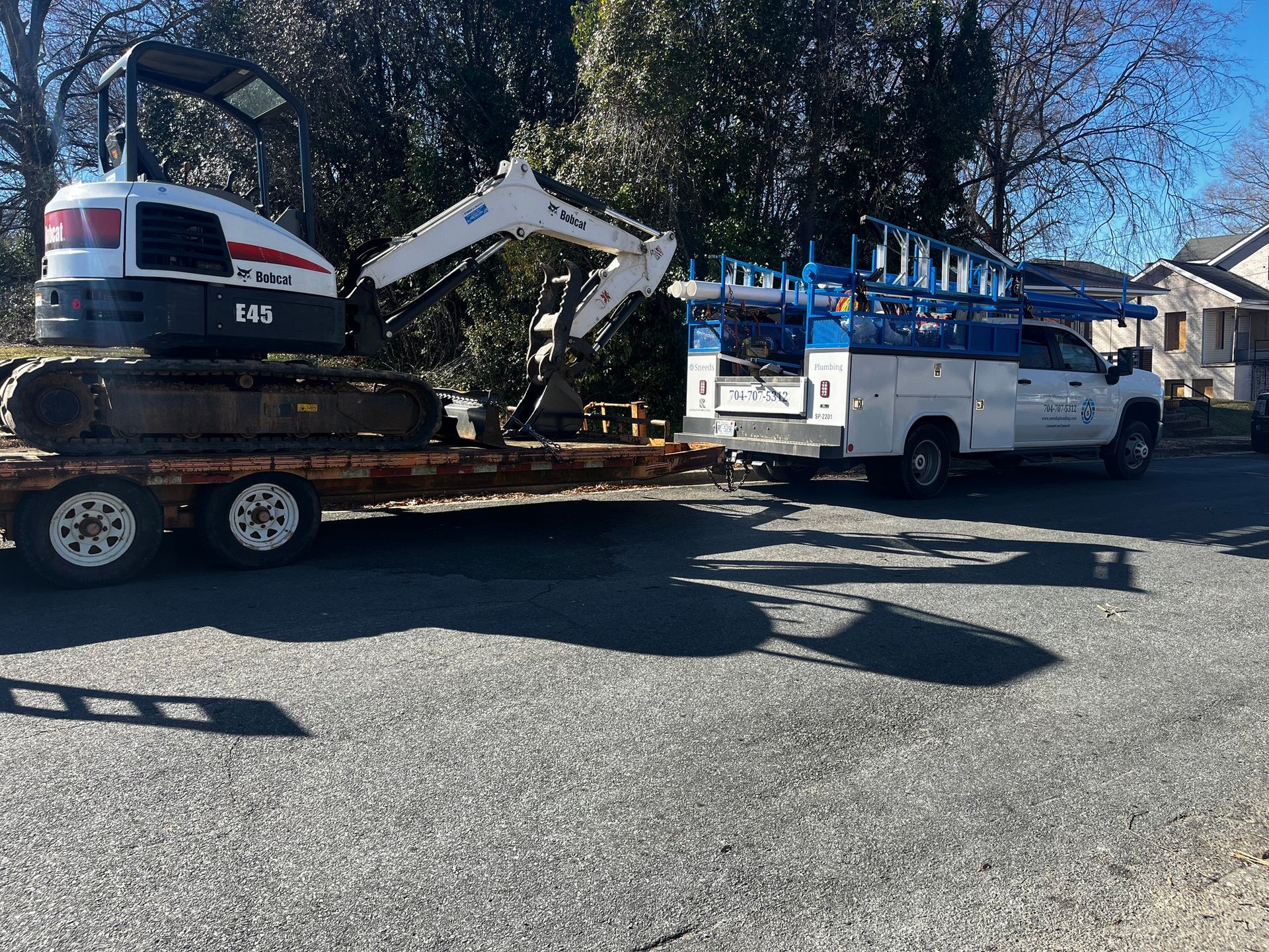 A bulldozer is being towed by a truck on a trailer.