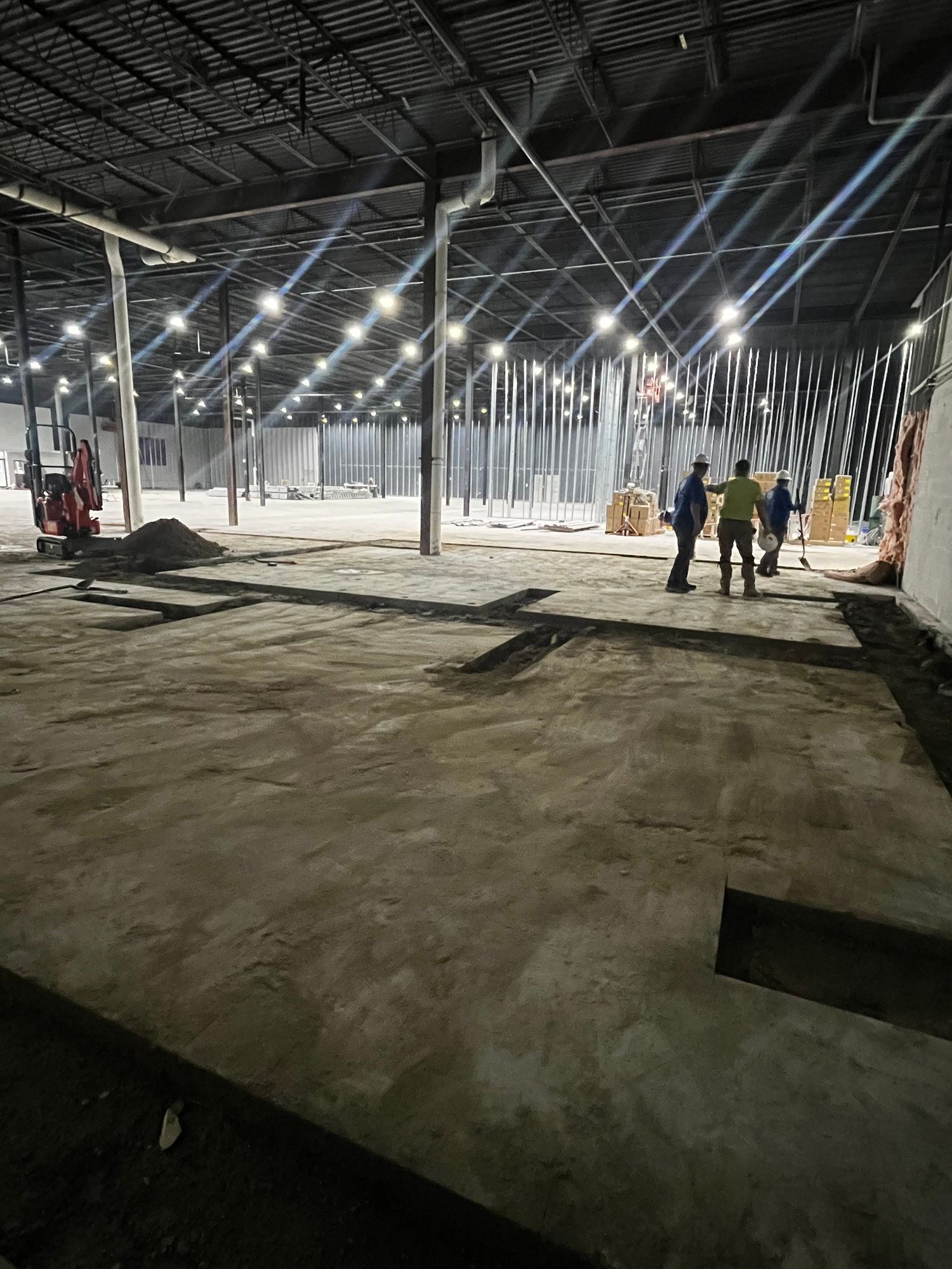 A group of people are standing in an empty warehouse at night.