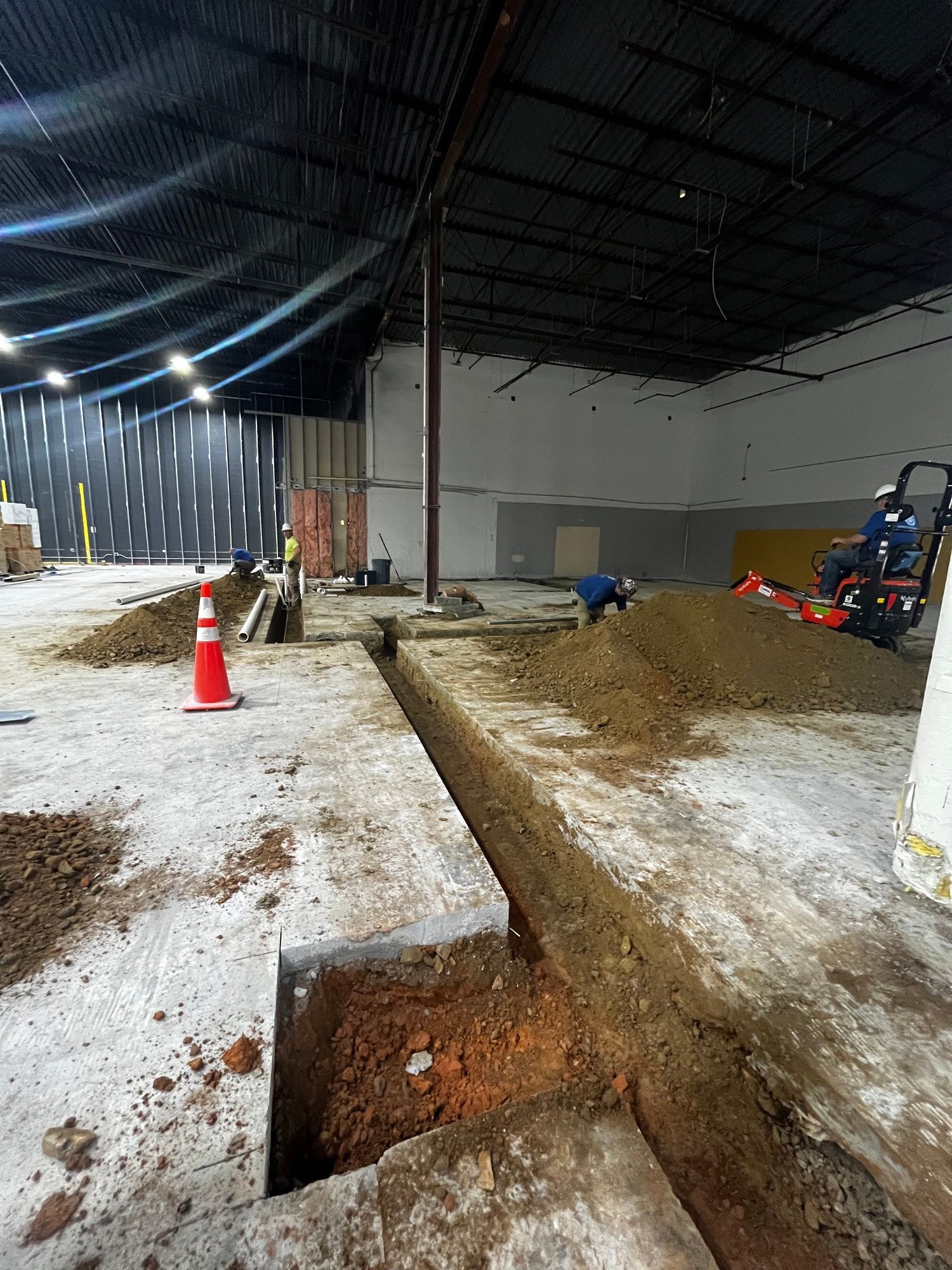 A man is digging a hole in the ground in a warehouse.