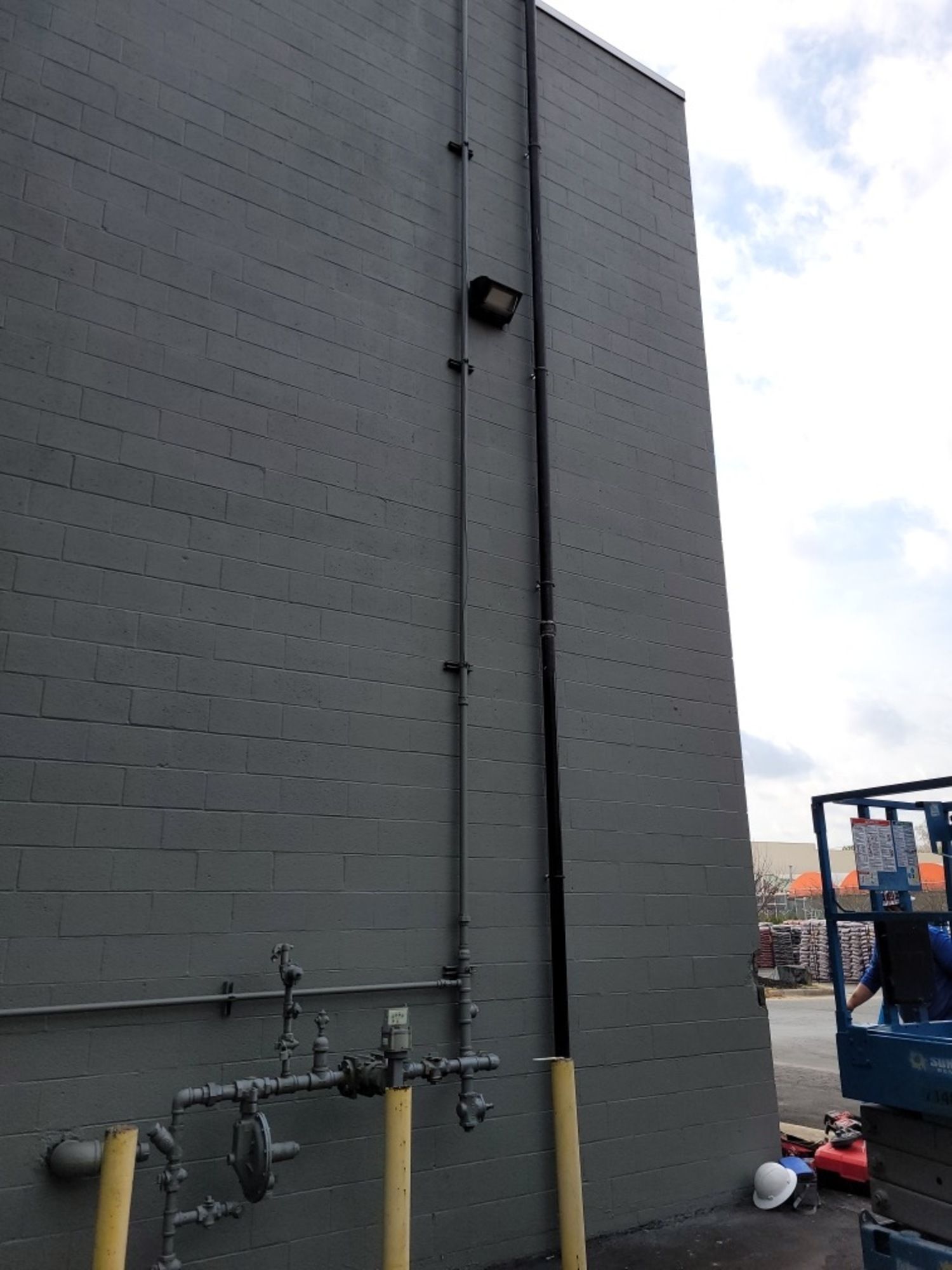 A gray brick building with a lot of pipes on it