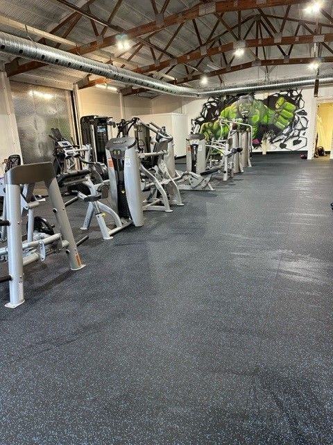 A gym with weight machines on a gray floor