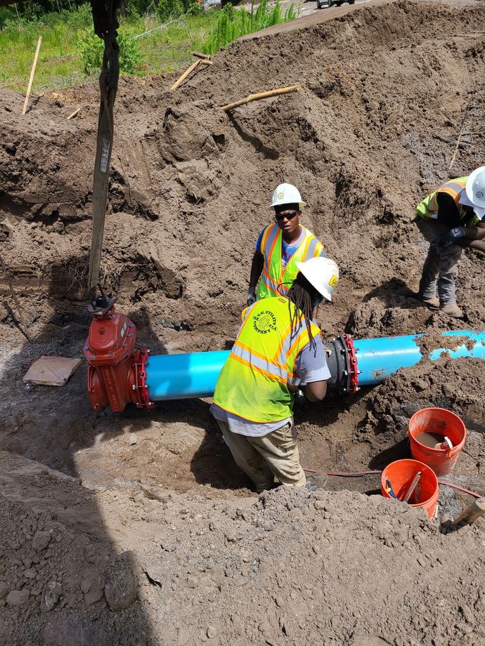 two workers attaching large DI pipes together