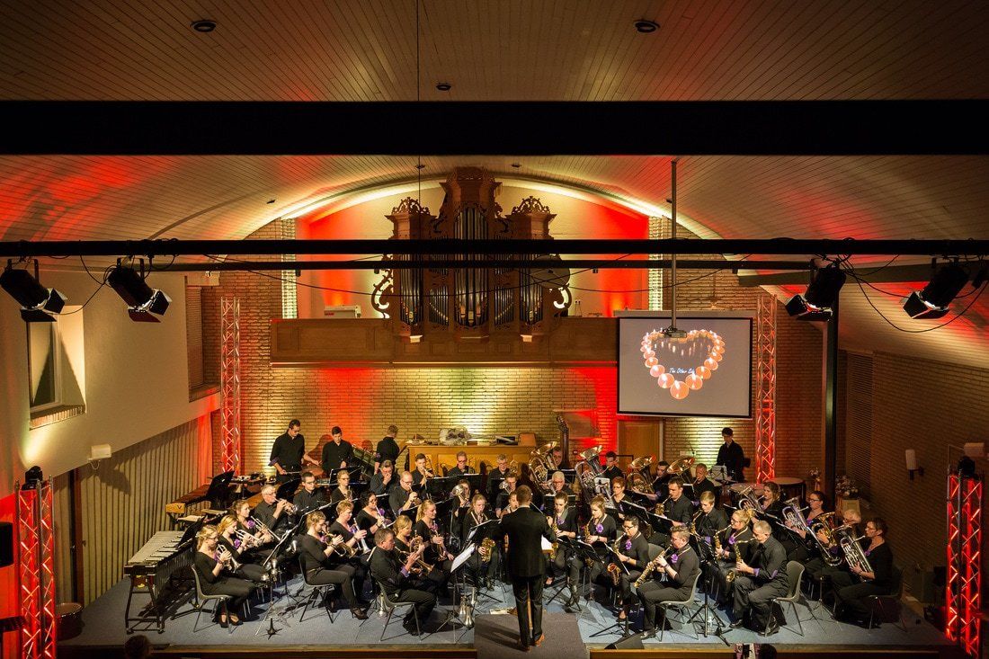 Orkest treedt op op een warm verlicht podium met een hartvormige lichtinstallatie op de achtergrond.