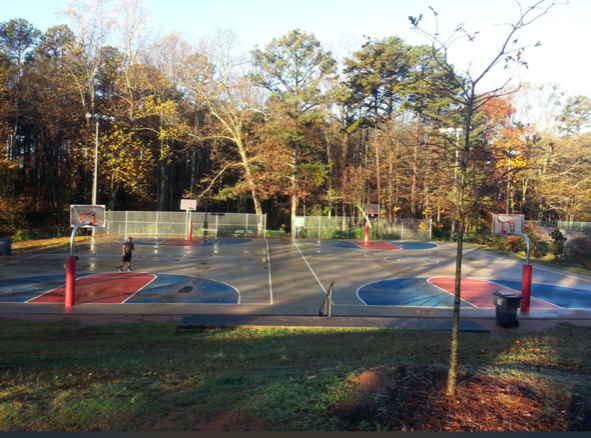 A basketball court in a park with trees in the background