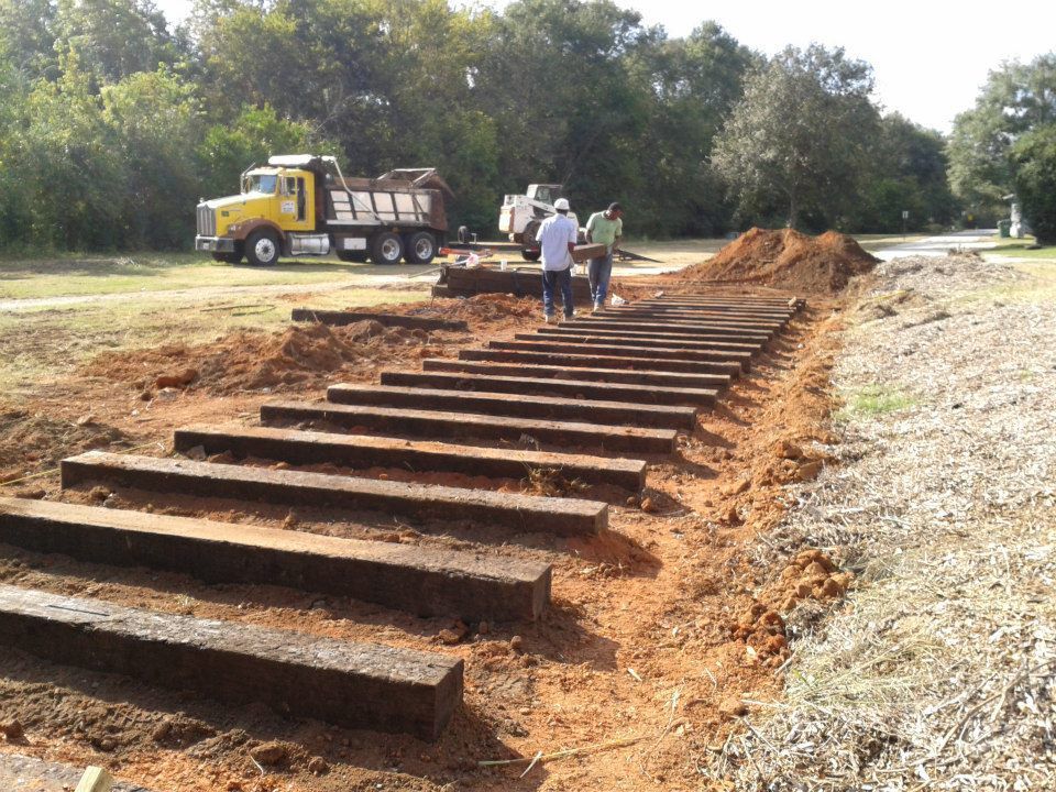 A yellow dump truck is parked next to a set of wooden steps