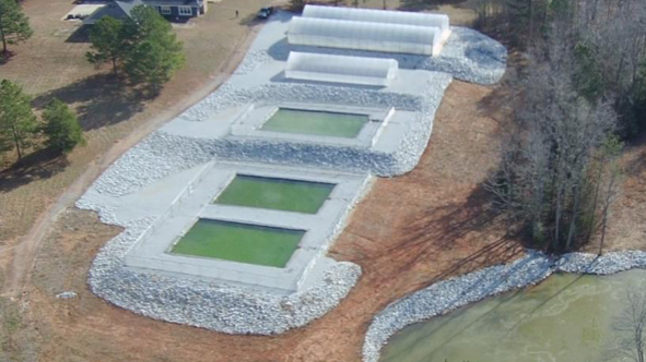 An aerial view of a swimming pool surrounded by rocks and grass.