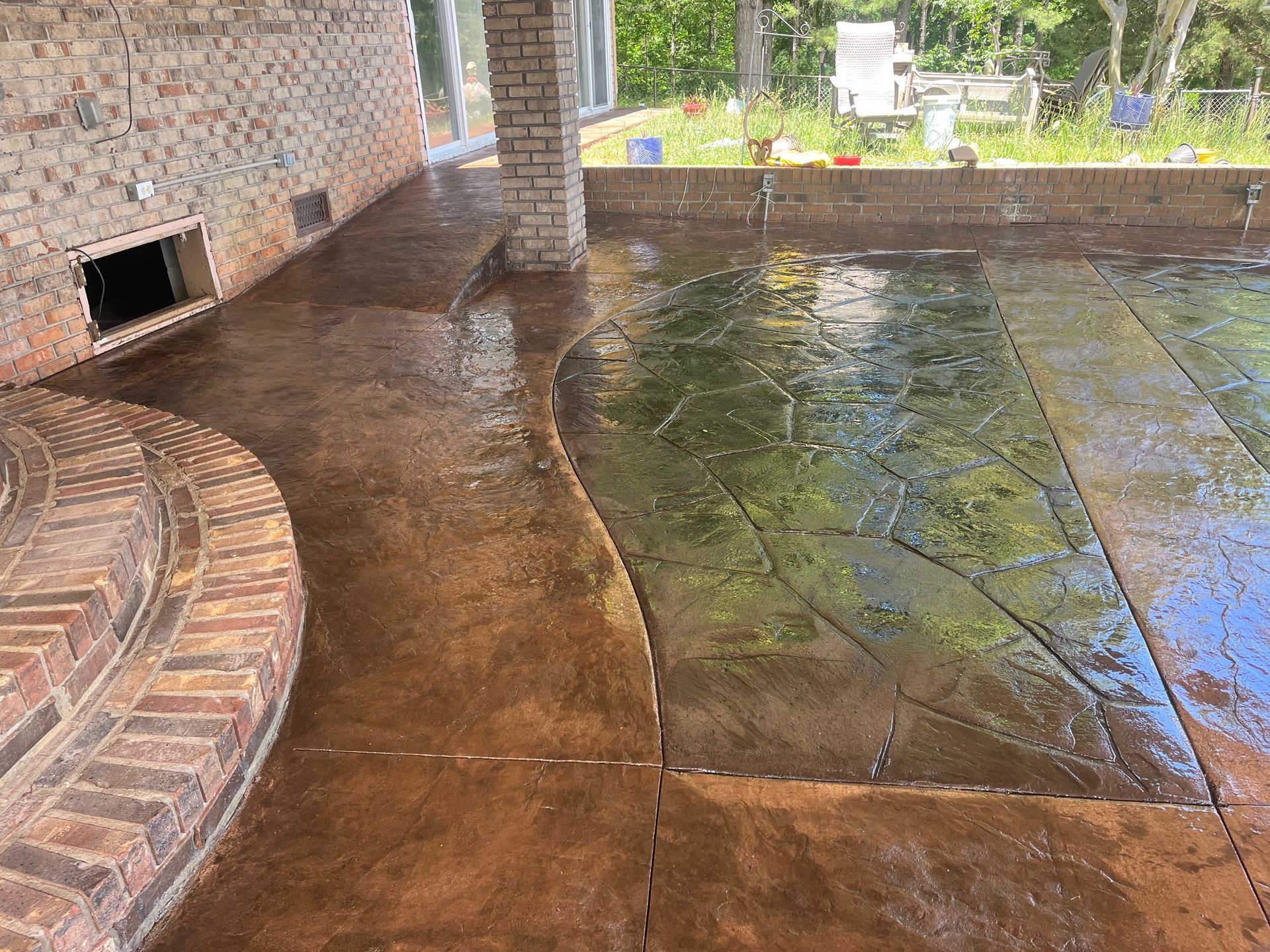A patio with a brick wall and a swimming pool in the background.