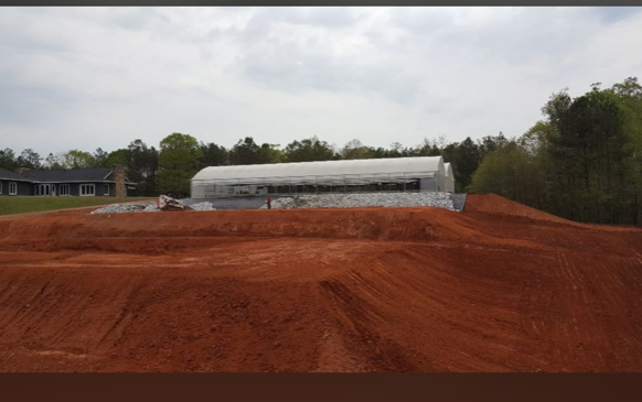 A large white building is sitting in the middle of a dirt field.
