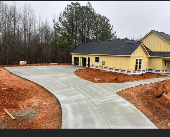 A yellow house with a concrete driveway in front of it