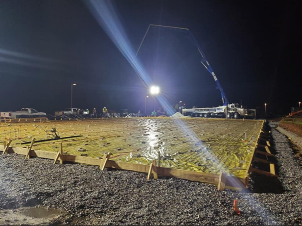 A construction site at night with a crane pumping concrete.