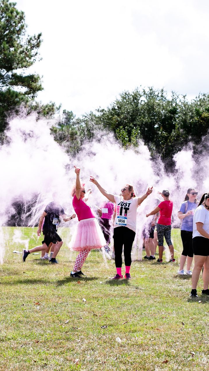 A woman in a pink tutu is standing in front of a crowd of people.