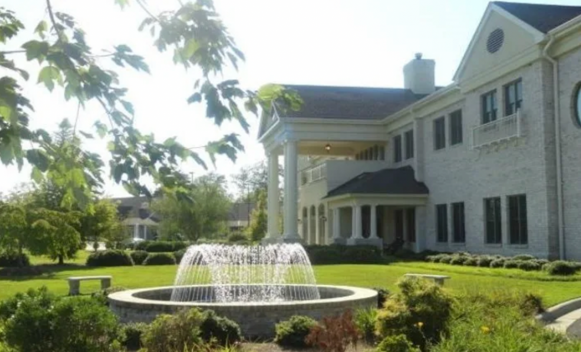 A large white building with a fountain in front of it