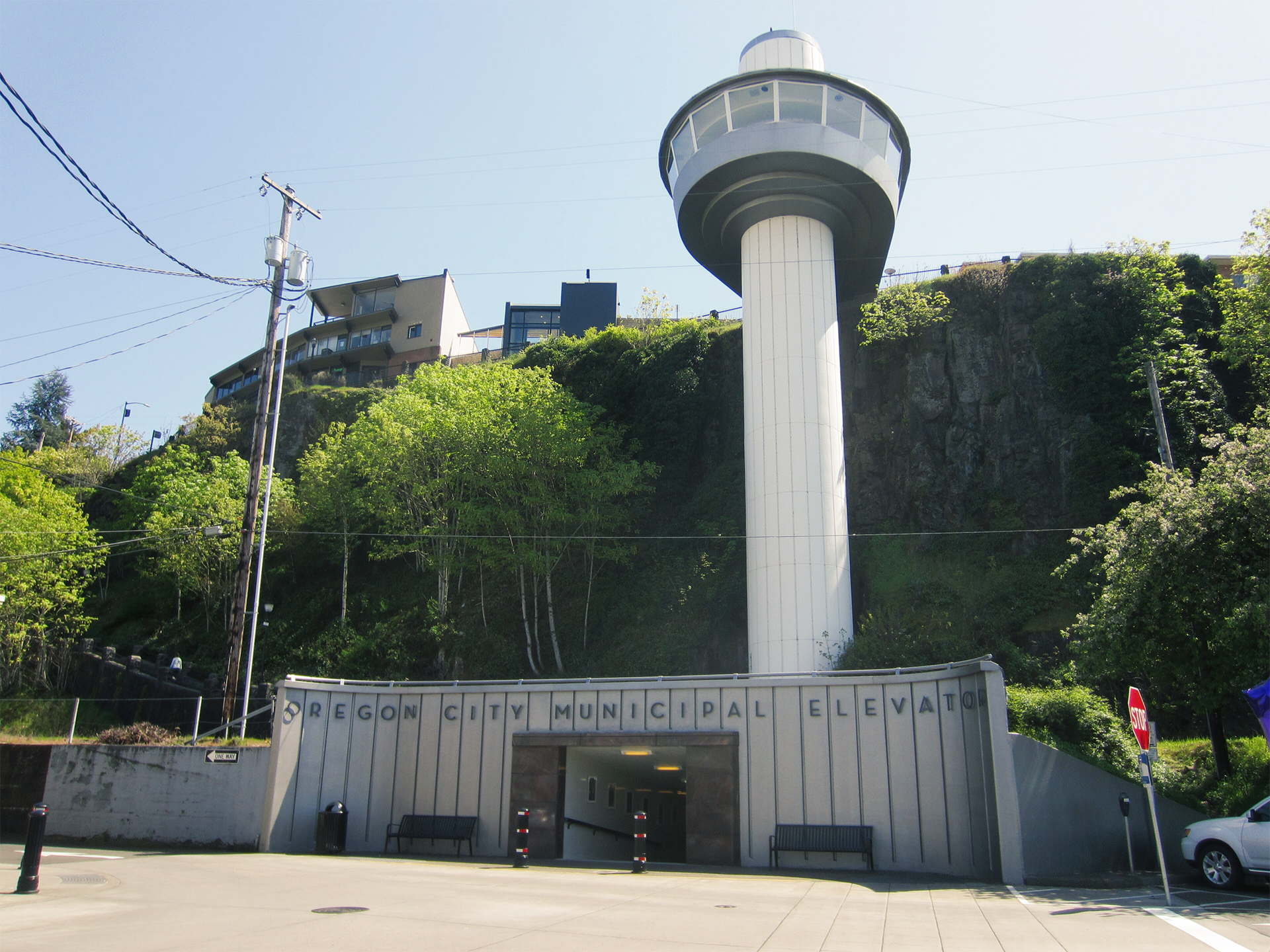 Tall observation tower above a gated entrance, surrounded by greenery under a clear sky.