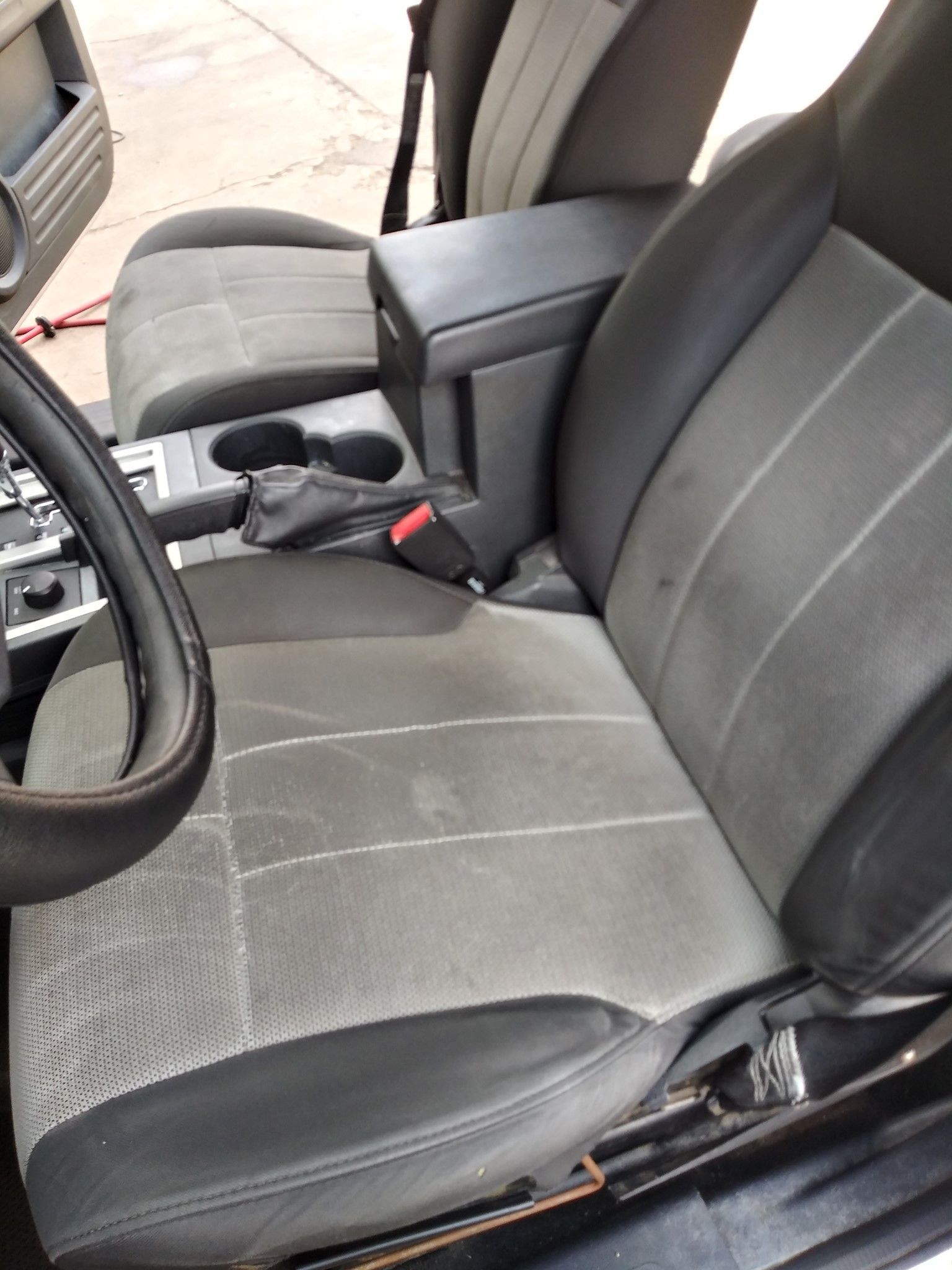 Black and gray car seat with visible wear and tear, centered in the vehicle's interior.