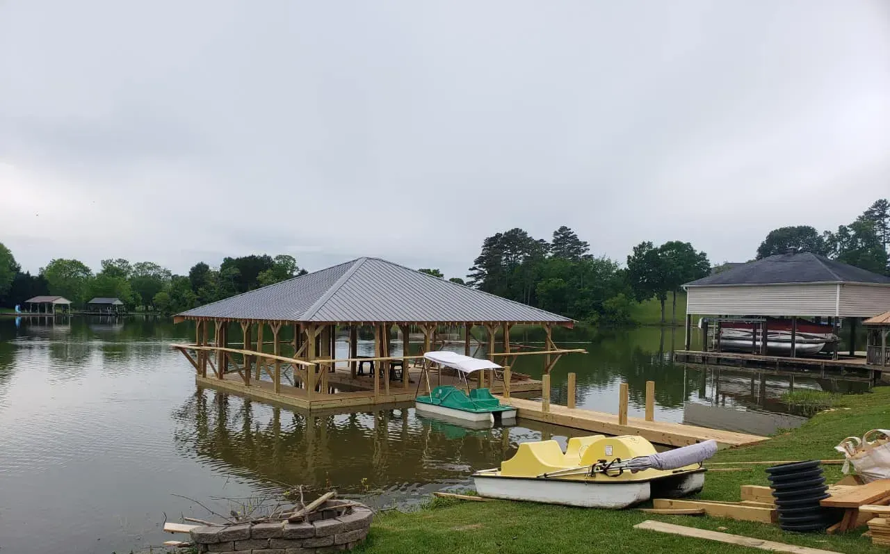 Lakeside pavilion and dock with small boats on calm water under a cloudy sky
