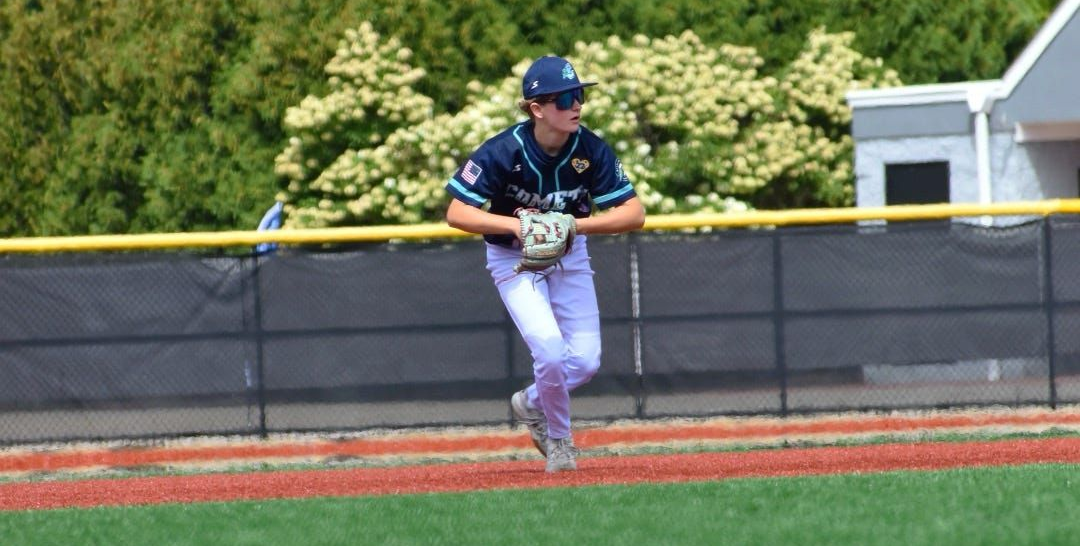 Baseball player in blue jersey and white pants fielding a ball on a grass field