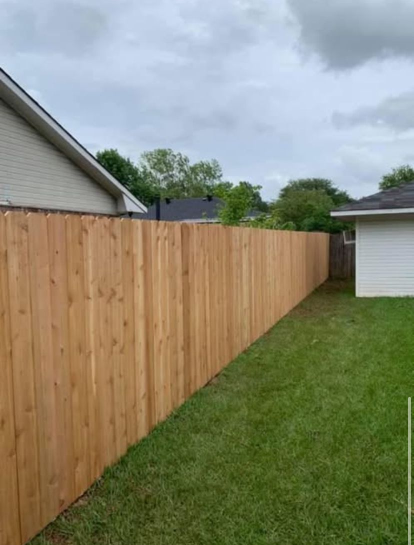 A wooden fence is in the backyard of a house.