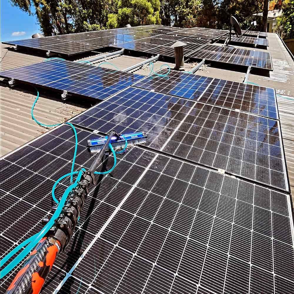 Solar Panels Being Cleaned on a Roof With a Long Handled Brush— Rapid Rinse Solutions in Shepparton, VIC