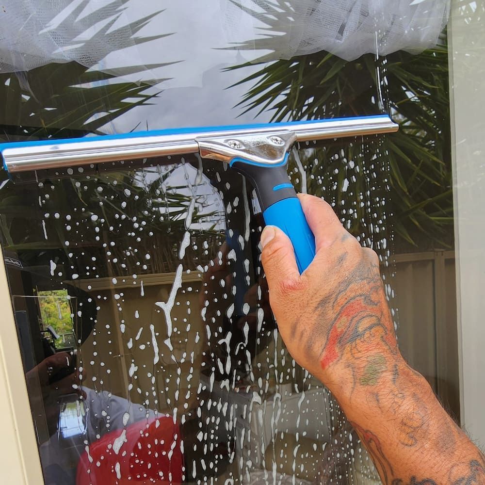 A Person With Tattoos Using a Squeegee to Clean a Soapy Window — Rapid Rinse Solutions in Shepparton, VIC