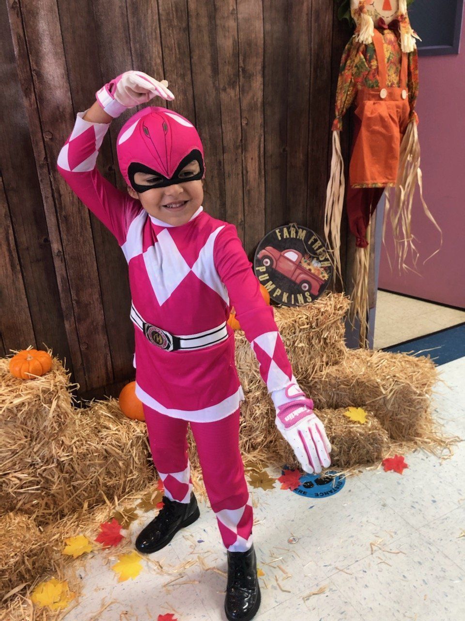 A little girl is dressed in a pink power ranger costume.
