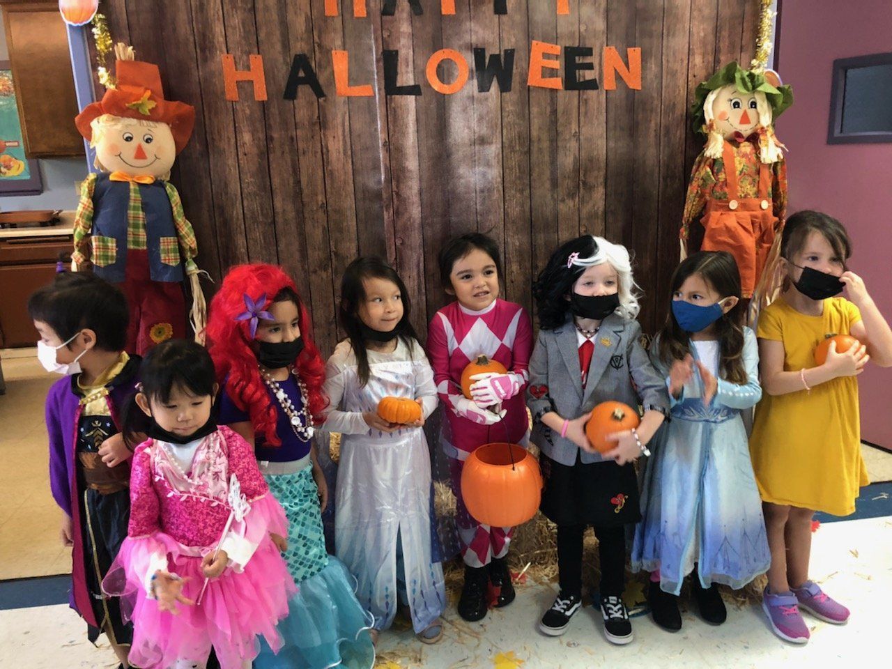A group of children in halloween costumes are posing for a picture.