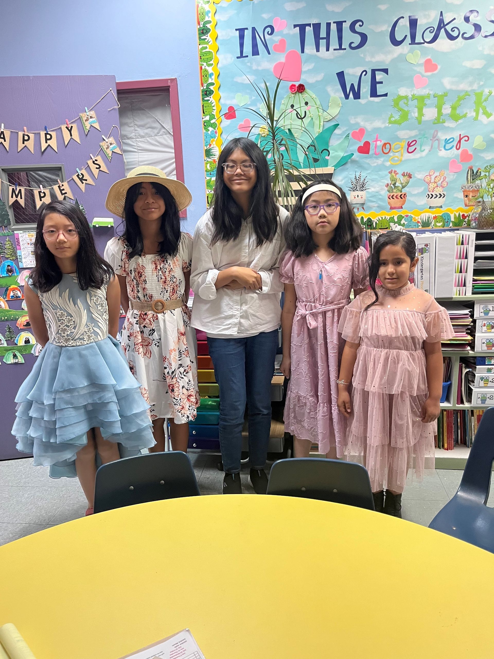 A group of young girls are posing for a picture in a classroom.