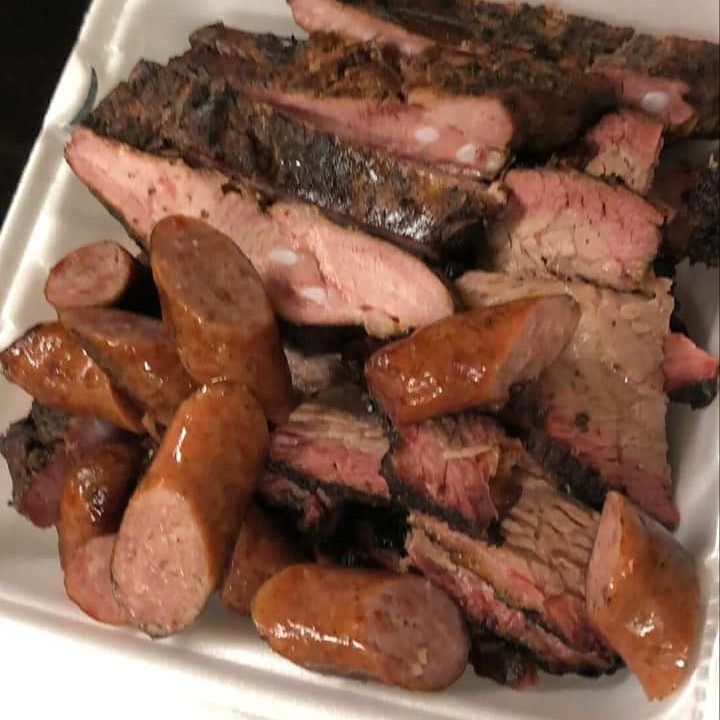 A styrofoam container filled with meat and sausages