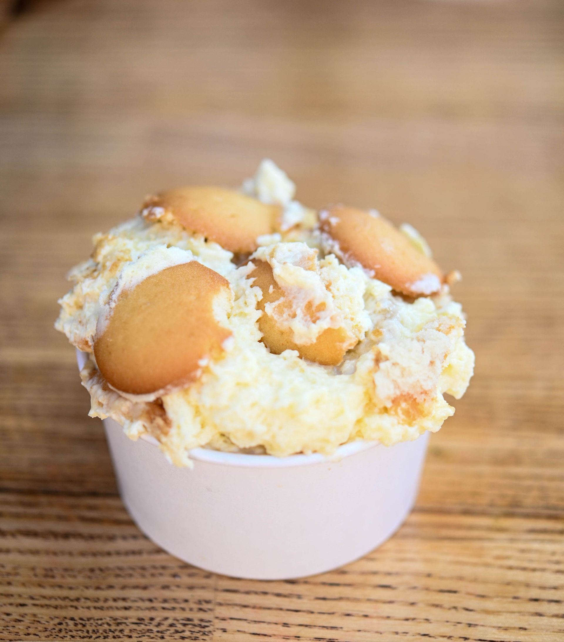 A white bowl filled with a dessert on a wooden table.