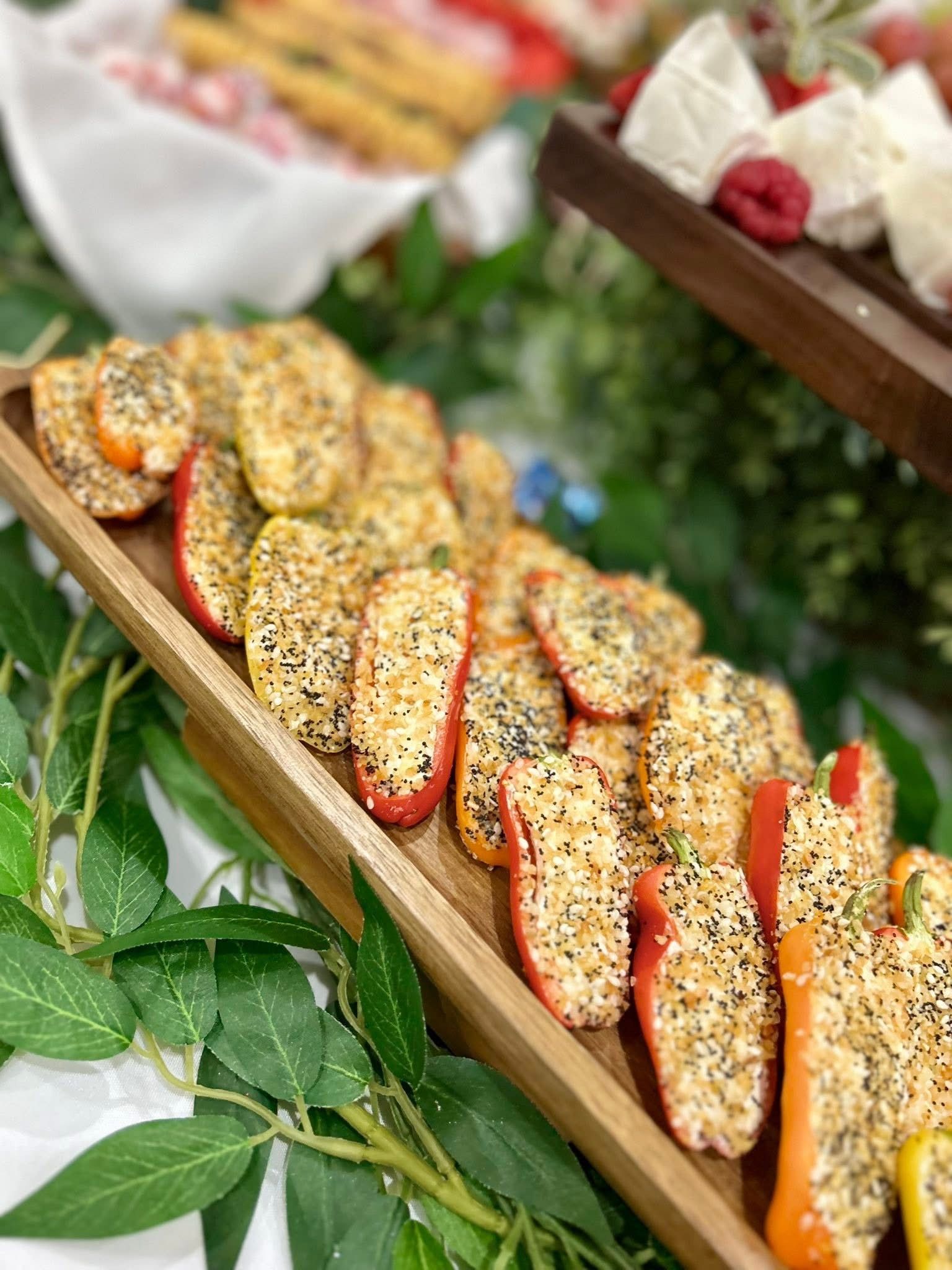 Tray of colorful, seeded bell pepper halves filled with cream cheese, garnished with herbs.