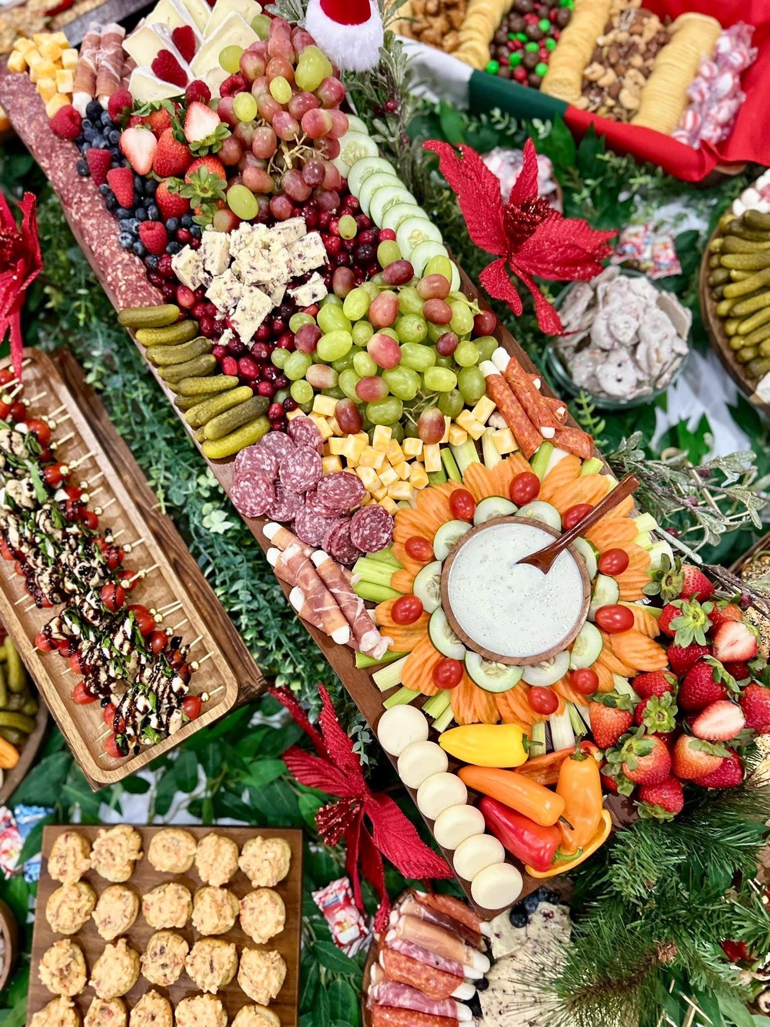 Charcuterie board with fruits, cheeses, meats, vegetables, and dip arranged for a holiday gathering.